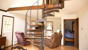 Eine Wendeltreppe in einem Zimmer mit Holzboden, einem Bett und zwei Sesseln.