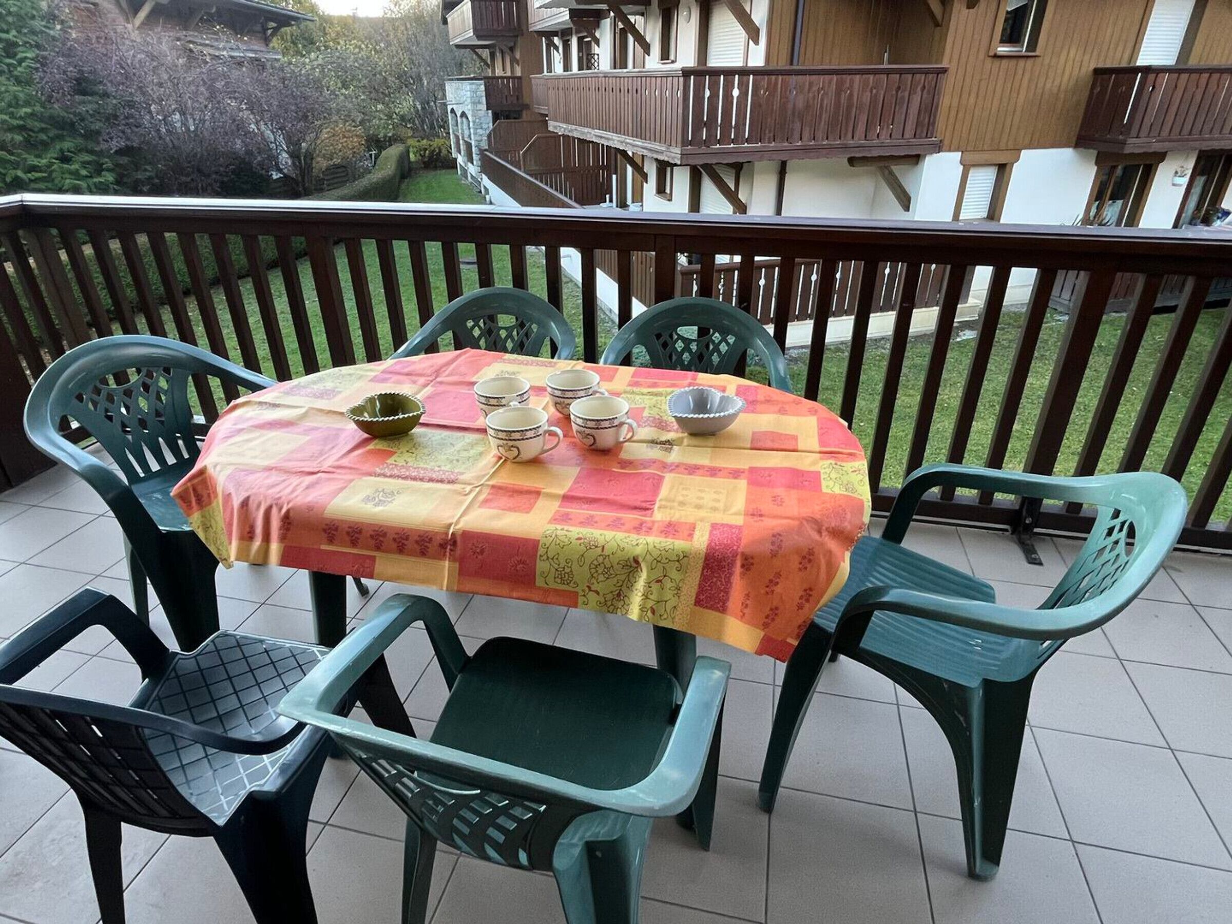 Een balkon met een tafel voor vier personen, omringd door groene stoelen.