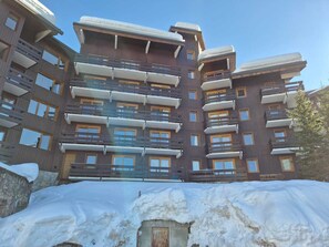 A multi-story hotel with balconies, a stone facade, and a snow-covered ground. - Bright studio at slope's foot, 3 pers - Méribel (Méribel)