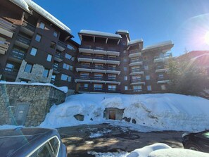 A multi-story hotel with balconies, stone facade, and a snow-covered ground. - Bright studio at slope's foot, 3 pers - Méribel (Méribel)