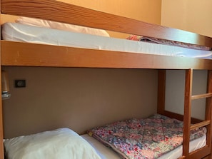 Una cama litera con estructura de madera y ropa de cama blanca.