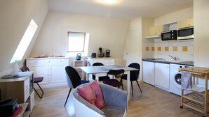 Un espacio habitable compacto con comedor, kitchenette y un rincón de descanso acogedor con sofá.