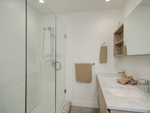 A modern bathroom with a glass-enclosed shower, a marble sink, and a wooden vanity. - Royal Vista - Exceptional Views, AC and lots of Amenities by Victoria Prime! (Victoria)