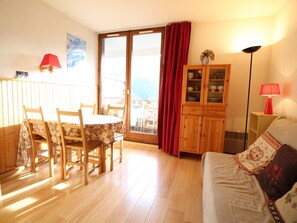 A cozy living room with a wooden dining table, chairs, a sofa, and a cabinet. - Studio for 4 pers with balcony at ski slopes (Flaine)