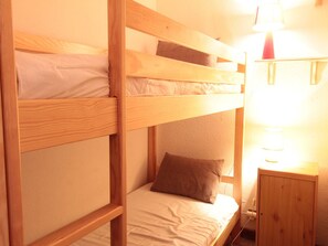 A bunk bed room with a wooden frame, a bedside table with a lamp, and a wall socket. - Studio for 4 pers with balcony at ski slopes (Flaine)