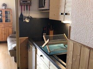 A compact kitchen with wooden cabinets, a dishwasher, and a drying rack. - Studio for 4 pers with balcony at ski slopes (Flaine)