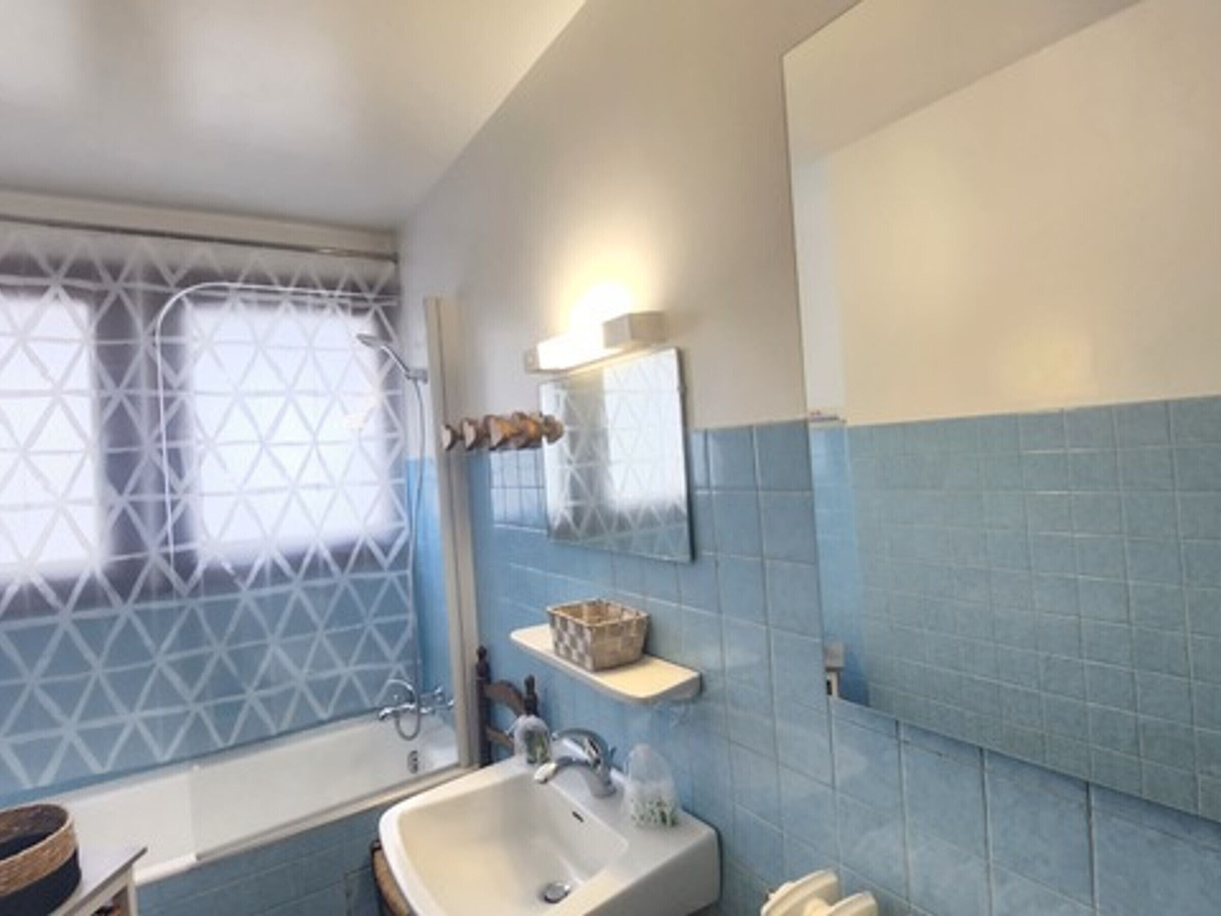 A bathroom with a bathtub, a sink, and a mirror.