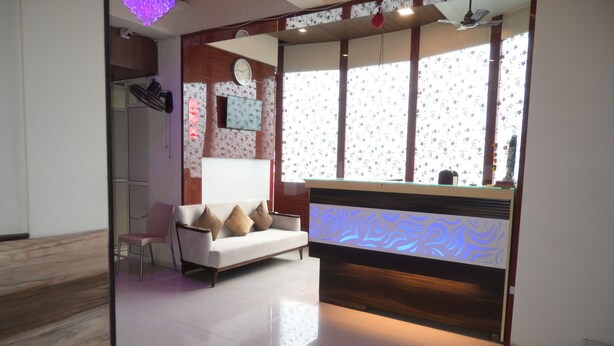 Un moderno salón con un sofá blanco, un mostrador de recepción de madera y un ventanal con cortinas estampadas de estrellas.