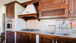 A kitchen with wooden cabinets, a gas stove, an oven, and a tiled backsplash.