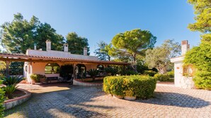 A courtyard with cobblestone paving, a covered patio area, and surrounding greenery.