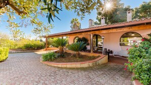 A courtyard with a tiled floor, a covered seating area, and a building with a tiled roof.