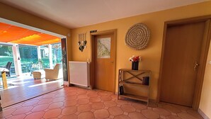 Ein geräumiger Raum mit sechseckigem Fliesenboden, einem Heizkörper, einer Holztür und einem an der Wand befestigten dekorativen Gegenstand.