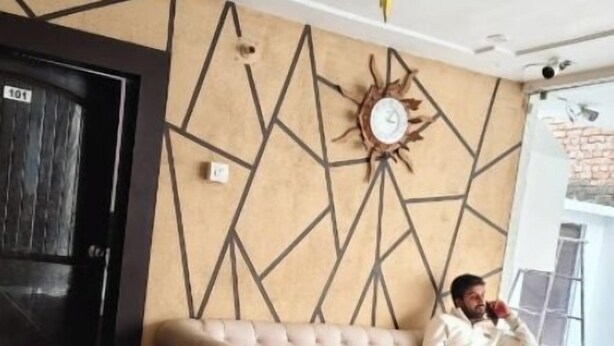 Un salón moderno con un sofá beige, una mesa de centro y un diseño geométrico en la pared.
