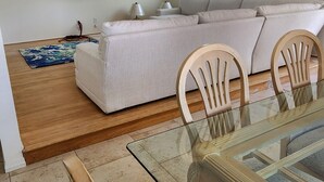 En stue med sofa, fjernsyn og spisebord med stole.