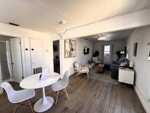 A modern living room with a dining area, a sofa, a TV, and a fireplace. - Grand Central Kava Loft Walk to Vibes (St. Petersburg)