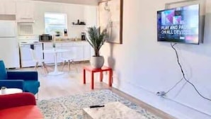 A modern living room with a red sofa, a marble coffee table, and a TV mounted on the wall. - Grand Central Kava Loft Walk to Vibes (St. Petersburg)