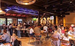 Un restaurant animé, doté de hauts plafonds, de poutres apparentes et d’un agencement varié des sièges, comprenant des tables et des chaises.