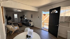 A living room with a sofa, chairs, a coffee table, and a door leading outside. - Grand Central Kava Loft Walk to Vibes (St. Petersburg)