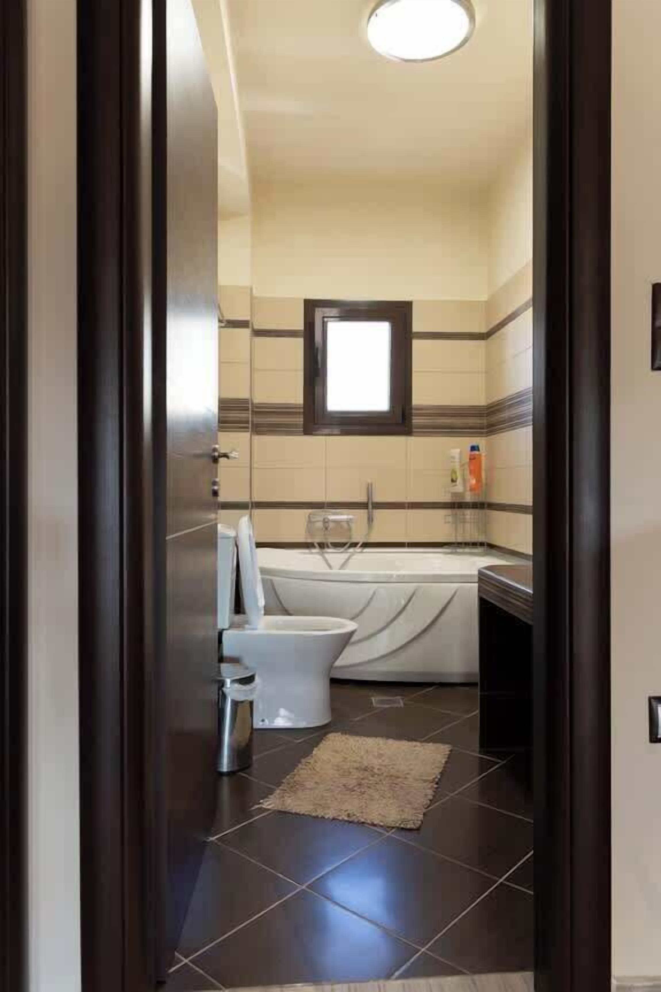 A narrow bathroom with a bathtub, toilet, and sink.