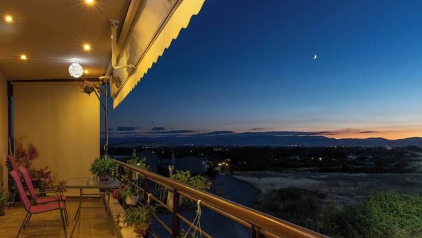 A balcony with a view of the landscape, a table with chairs, and potted plants. - The Sunset Haven Kastoria Modern Lake Elegance (Kastoria)