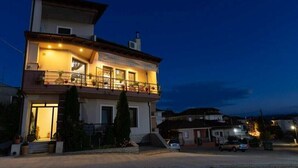 A two-story residential building with a balcony, a visible entrance, and a driveway. - The Sunset Haven Kastoria Modern Lake Elegance (Kastoria)