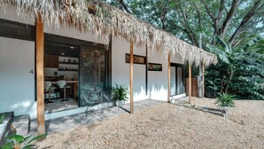 Una casa moderna con tetto di paglia, ingresso con porta in vetro e vialetto ghiaioso.