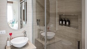 A modern bathroom with a glass shower enclosure, a round mirror, and a vanity with a sink. - Romantic Suite with jacuzzi near Vatican (Room 2) (Roma)