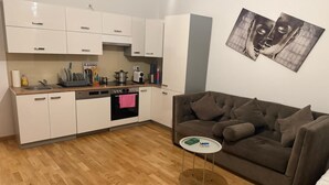 A compact living space with a kitchenette, a brown sofa, and a small round table. - Comfort 1BR Studio Near Matzleinsdorfer (Vienna)