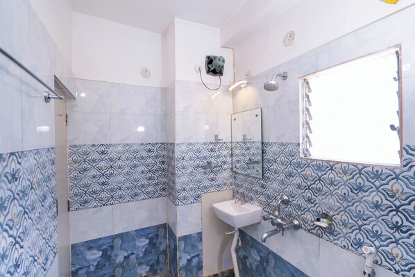 A bathroom with a shower, a sink, and a mirror. - Sonar Puri Unit 1 (Puri)
