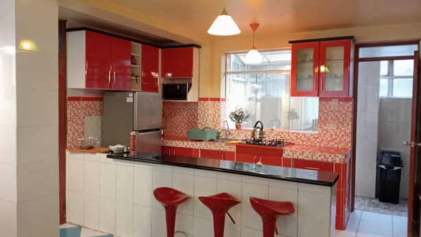 Una cocina moderna con gabinetes rojos, una estufa a gas y una ventana con vista a la calle.