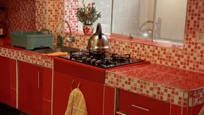 Una cocina con gabinetes rojos, estufa a gas, un lavamanos y una ventana con vistas.