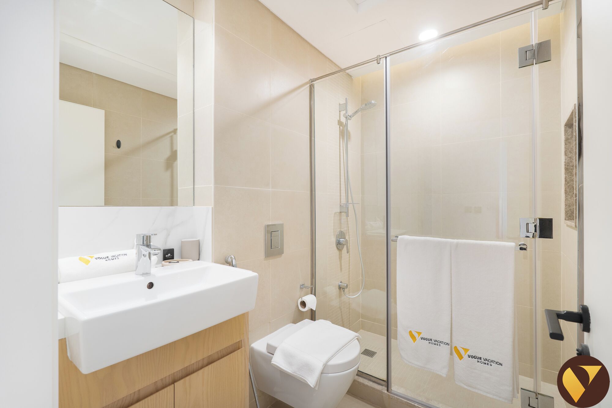Een moderne badkamer met een douchecabine van glas, een wit wastafel en een toilet.
