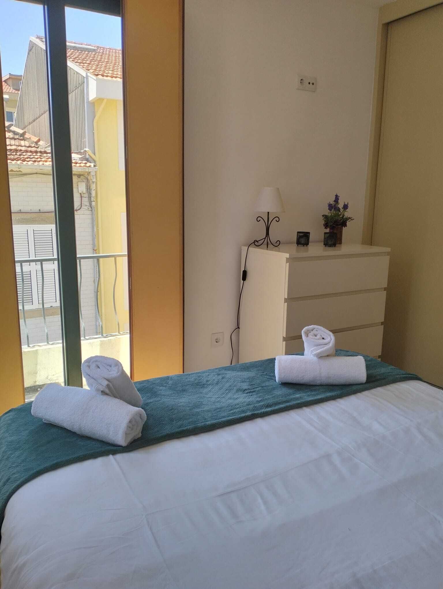 Een hotelkamer met een bed, een dressoir, een lamp en uitzicht op gebouwen.