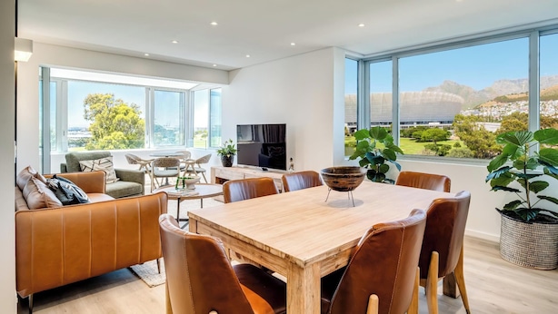 Ein modernes Wohnzimmer mit Essbereich, großen Fenstern und Blick auf die Stadt.