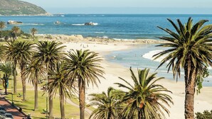 A beach with palm trees, a clear sky, and the ocean. - Camps Bay Seaside Beach View Apartment Palm Bay (Cape Town)