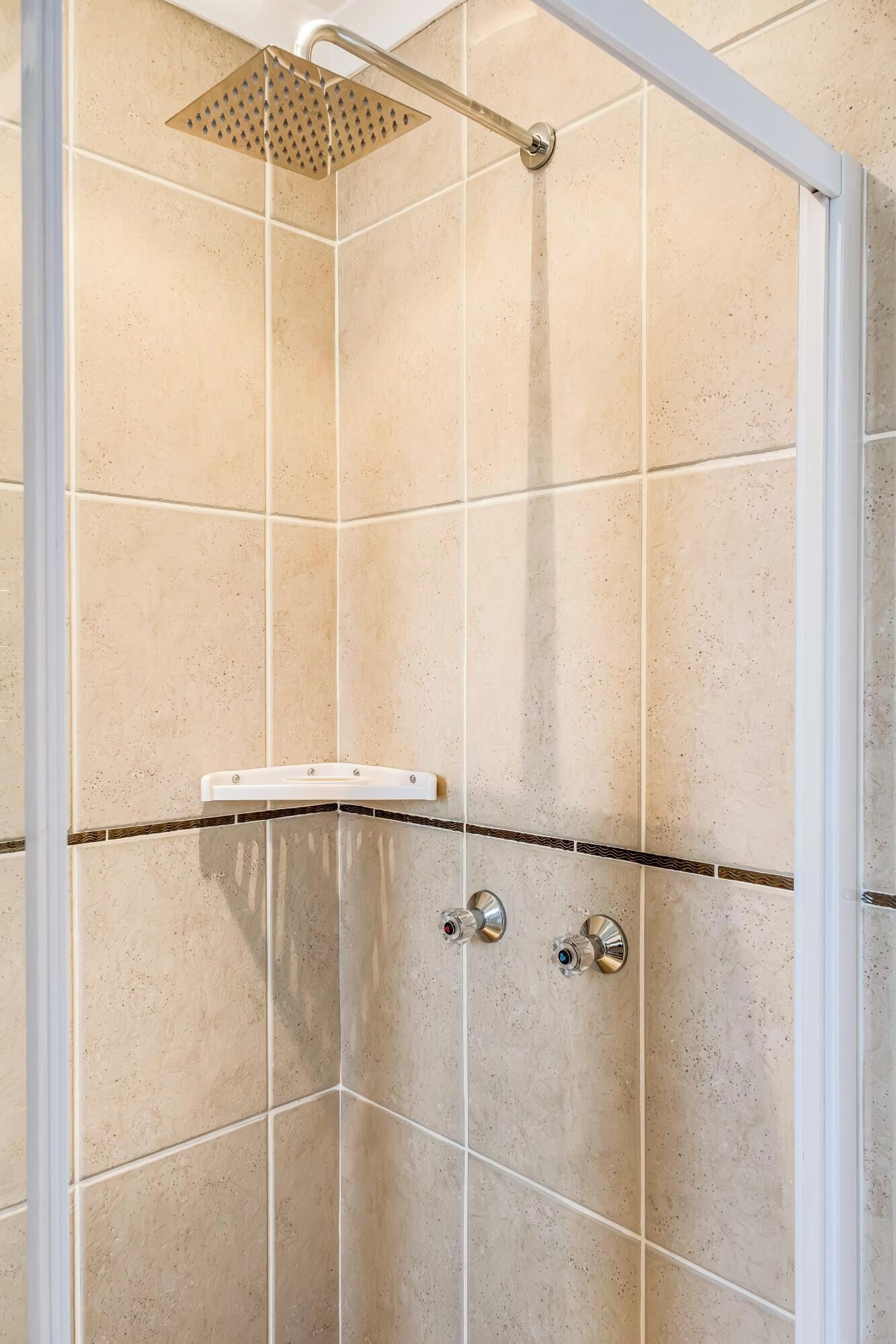 A shower with a handheld showerhead, a handheld shower bar, and a wall-mounted control panel.