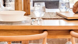 A dining table set with plates, glasses, and a bread roll, with a view of the ocean through a window. - Camps Bay Seaside Beach View Apartment Palm Bay (Cape Town)