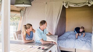 Eine Zelteinrichtung mit einem Bett, einem Tisch mit elektronischen Geräten und einer Person, die auf das Bett steigt.
