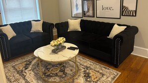 A living room with two black sofas, a round coffee table, and a patterned rug. - Spacious 2 bedroom with a Deck in center city (Philadelphia)