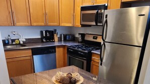 A kitchen with wooden cabinets, a stainless steel refrigerator, a microwave, and a sink. - Spacious 2 bedroom with a Deck in center city (Philadelphia)