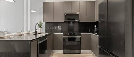 Una cocina moderna con una isla central, electrodomésticos de acero inoxidable e iluminación colgante.