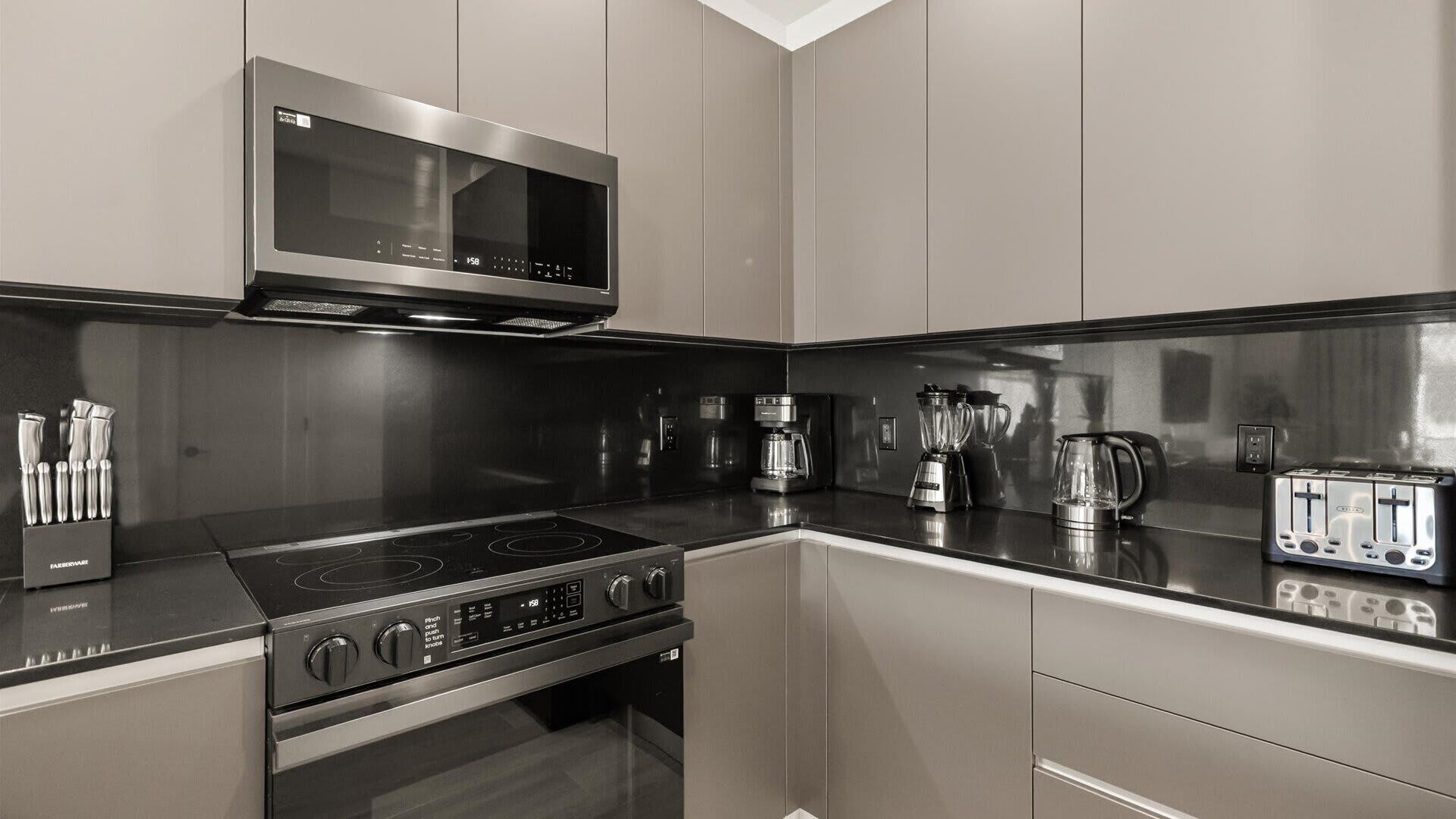 Uma cozinha moderna com eletrodomésticos de aço inoxidável, incluindo micro-ondas, fogão e torradeira.
