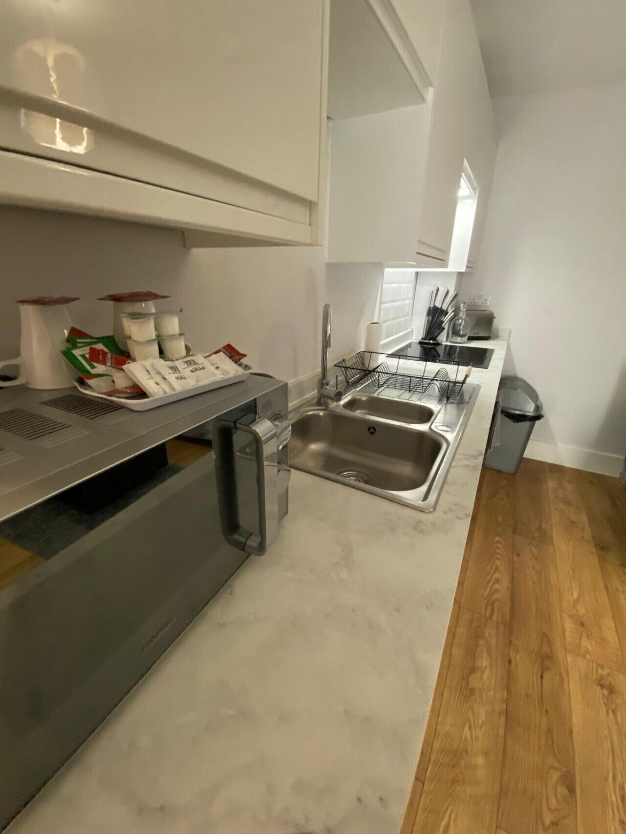 A modern kitchen with a stainless steel sink, a built-in oven, and a compact countertop.