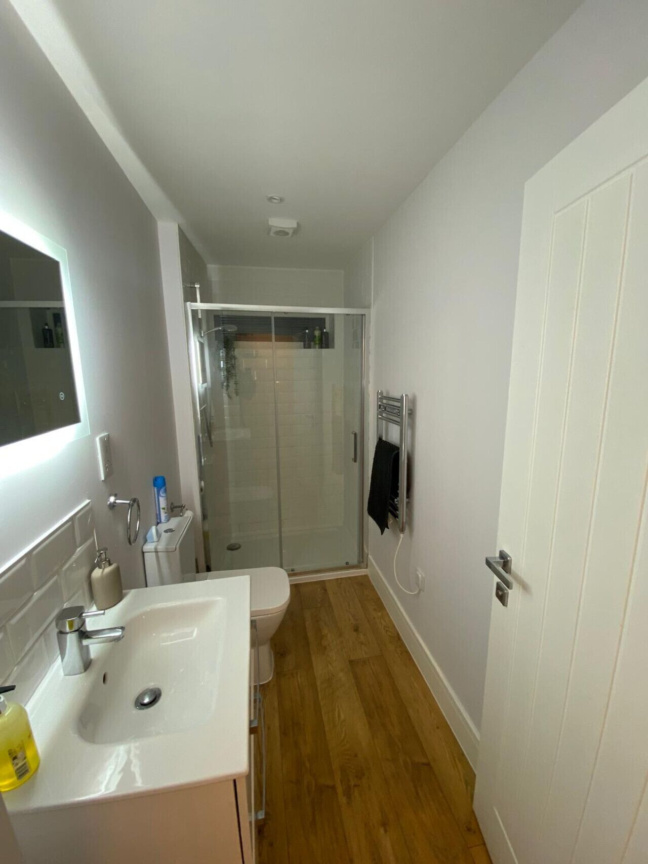 A bathroom with a white sink, toilet, and glass shower enclosure.