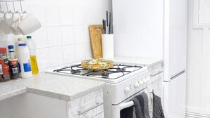 Een keuken met een gasfornuis, oven en een witte koelkast.