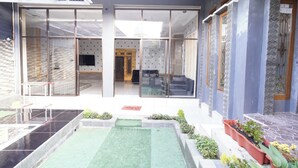 Een modern hotel met een glazen gevel, een binnentuin met kunstgras en plantenpotten.