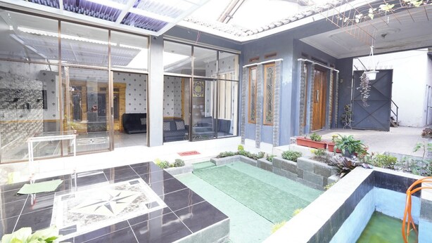 Een modern huis met een glazen patio, een klein zwembad en een tuin met potplanten.