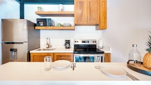 Une cuisine moderne avec des meubles en bois, des appareils en acier inoxydable et un plan de travail blanc.