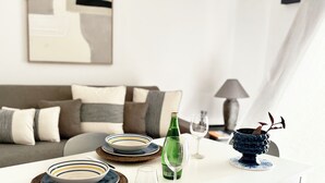 Un comedor con una mesa blanca dispuesta con platos, una copa y una botella.