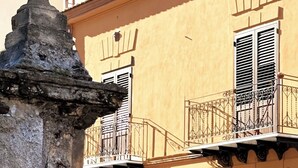 Un edificio con una fuente de piedra, balcones con barandillas de hierro forjado y un cartel con el número 50 en la pared.